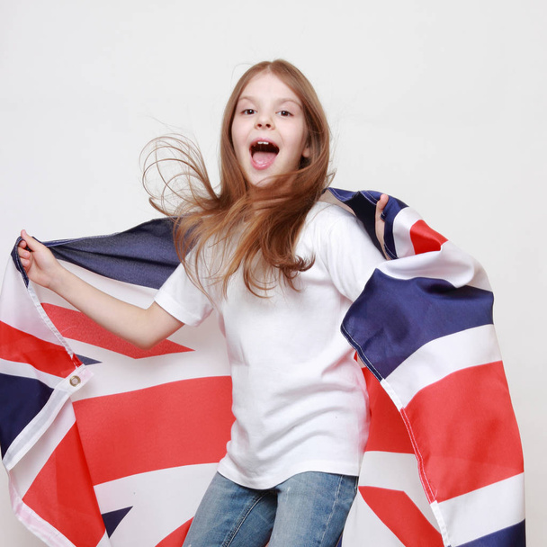 Happy young girl holding a flag of of Great Britain (British flag) - Foto, imagen