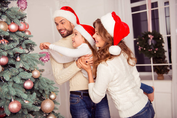 Mom, dad and little daughter decorating christmas tree - Photo, Image