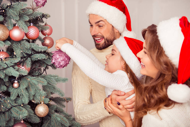 Portrait of happy family decorating christmas tree together - 写真・画像