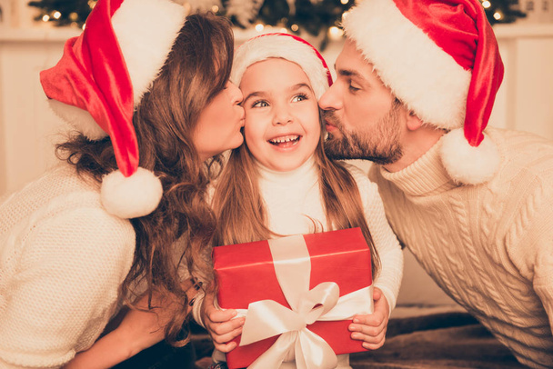 Happy parents kissing daughter and giving xmas present  on bed - Foto, Imagem