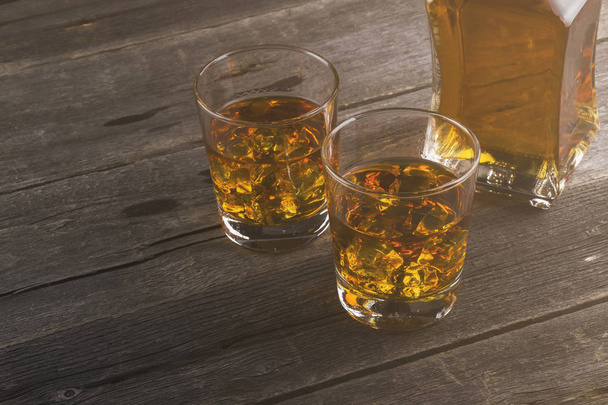 Whisky in two glasses on a dark wooden background. Toning - Photo, image