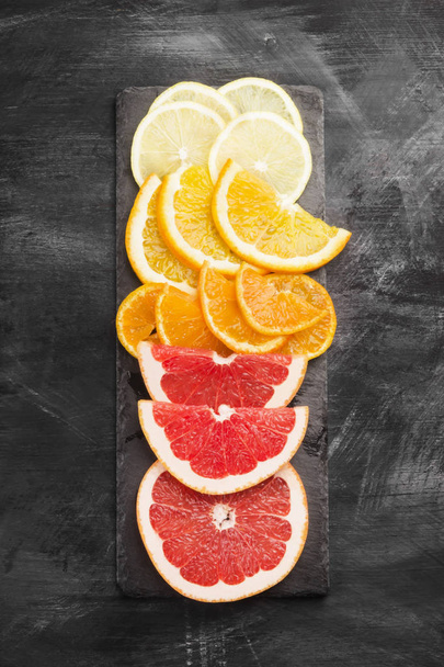Various citrus: orange, lemon, tangerine, grapefruit on a dark background. Top view. Toning. - Foto, Imagem