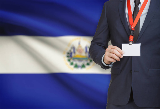 Zakenman kaart naambadge te houden op een lanyard met een nationale vlag op de achtergrond - El Salvador - Foto, afbeelding