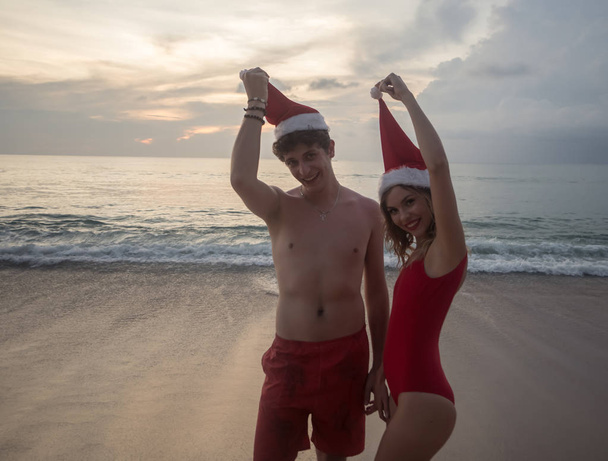 Couple portant un chapeau de Père Noël à la plage
 - Photo, image