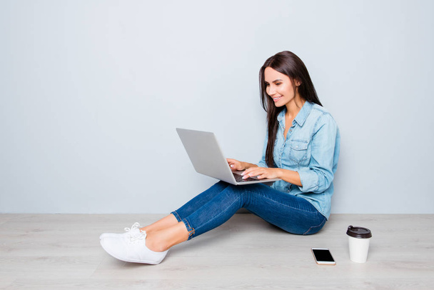 Young smiling woman working on laptop while sitting on floor - Fotografie, Obrázek