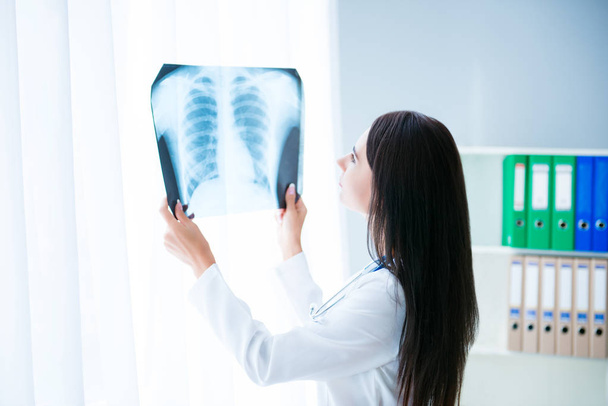 Female doctor looking at X-rays picture of patient's lung - Photo, image