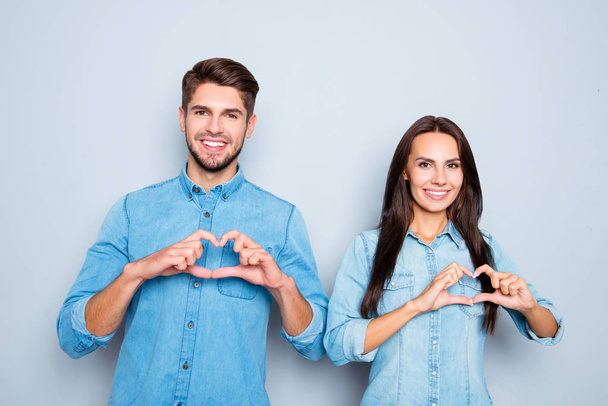 Portrait of cheerful man and woman in love gesturing heart - Foto, afbeelding