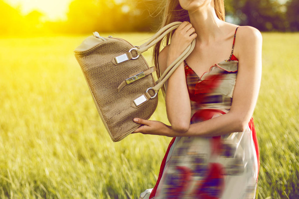 Menina segurando saco de mão ao ar livre sobre a natureza ao pôr do sol tempo
 - Foto, Imagem