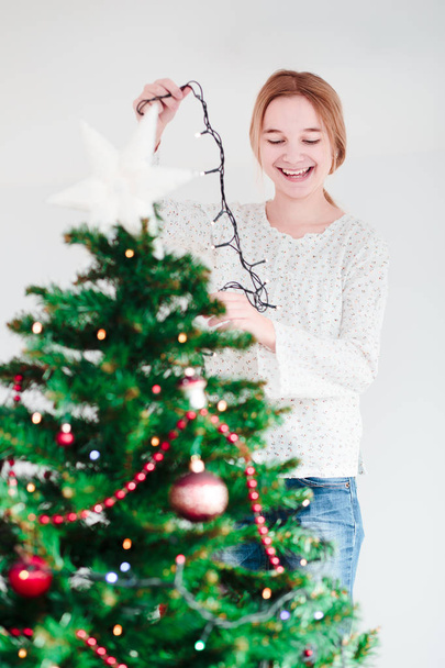 Young girl decorating Christmas tree with lights - Zdjęcie, obraz
