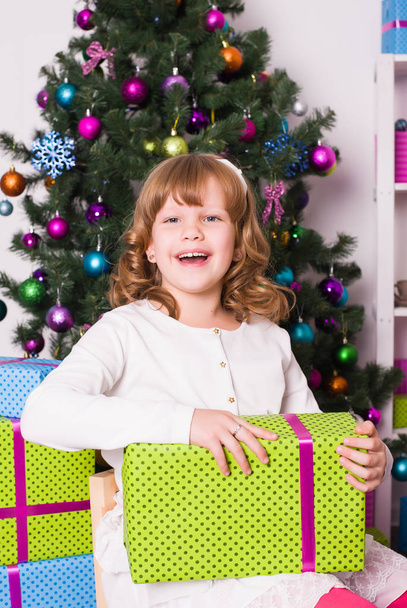 Fille avec un cadeau assis près de l'arbre de Noël
 - Photo, image