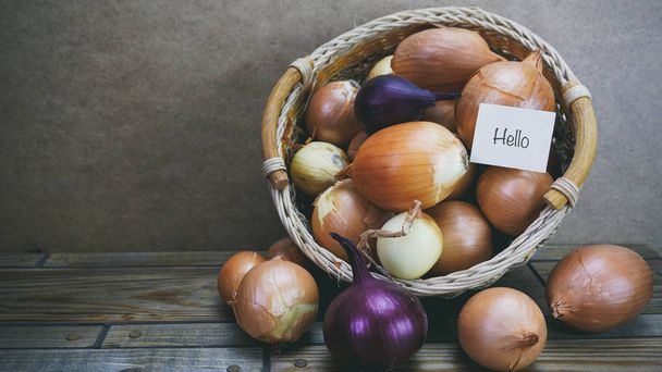Onions in a wooden basket, word on paper - Φωτογραφία, εικόνα