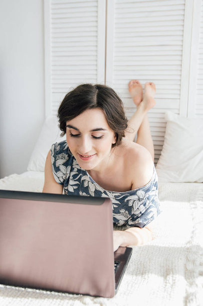 Girl looking at the laptop on the bed  - Photo, Image