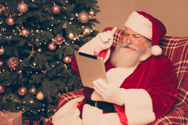 Excited serious modern Santa Claus wearing red costume holding t - Foto, Imagen