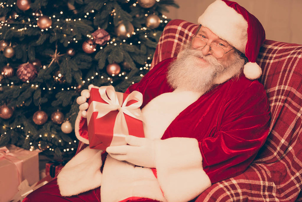 Happy Santa Claus sitting on chair in living room near christmas - Фото, изображение