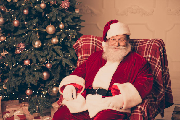 Happy Santa Claus sitting on chair in living room near christmas - Фото, зображення