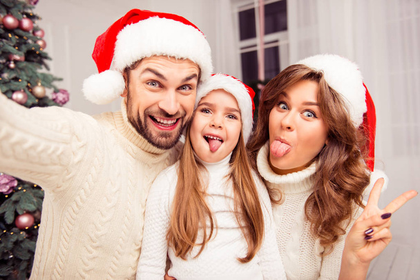 Cheerful family making comic xmas selfie and showing tongues - Foto, Imagen