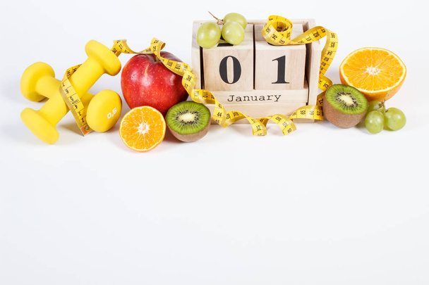 Cube calendar, fruits, dumbbells and tape measure, new years resolutions - Foto, Bild
