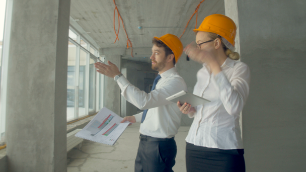 Business people, man and woman discussing construction plan, walking at a construction site. Steadycam shot. Close up. - Filmmaterial, Video