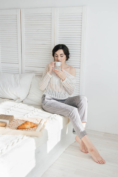 Girl drinking coffee and a croissant in bed  - Foto, Bild
