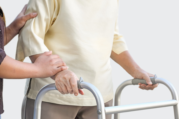 Senior vrouw met behulp van een walker met verzorger - Foto, afbeelding