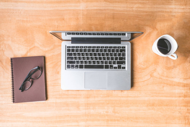 Pohled shora Laptop notebook, brýle a šálek kávy na dřevěný stůl pozadí. - Fotografie, Obrázek