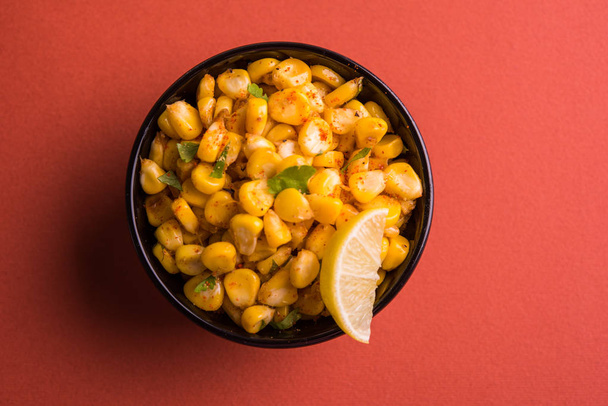 Сваренный органический желтый сладкий кукурузный масала или кукурузный чат, приготовленный с использованием масла или кукурузного чата, чат масала и лимон, любимые индийские закуски
  - Фото, изображение