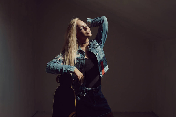 Pretty blonde woman with longboard in dark room - Photo, Image