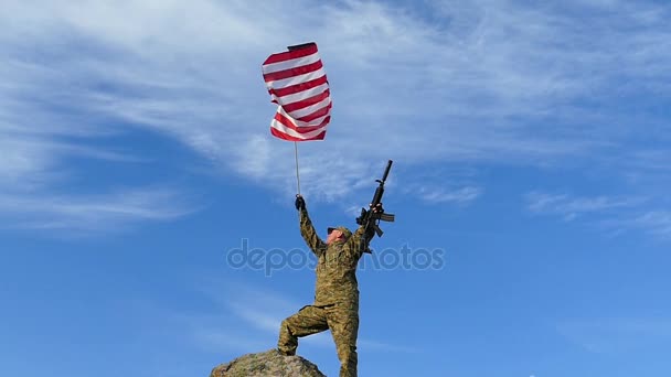 Солдат з гвинтівки хвилі американський прапор проти синього неба. Повільний рух - Кадри, відео