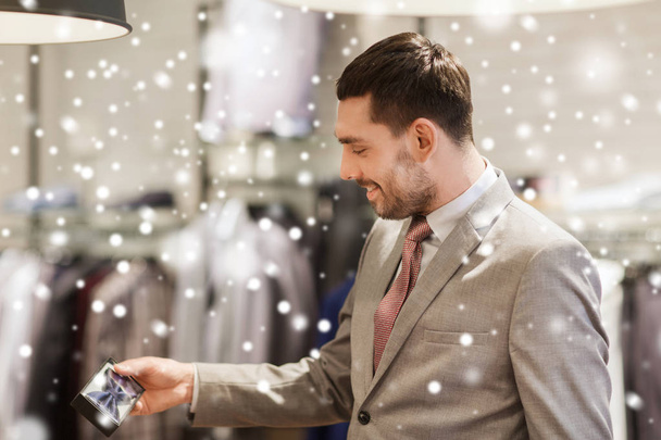 happy young man choosing bow-tie in clothing store - Fotó, kép