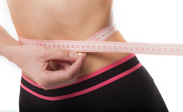 Vrouw meten van haar slanke lichaam op witte achtergrond. Begrip gezondheid. - Foto, afbeelding