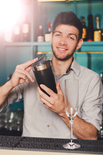 Молодий красивий бармен в барі трясе і змішує алкогольний коктейль
 - Фото, зображення