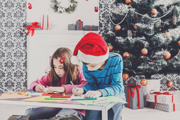 Χαριτωμένα παιδιά γράφοντας επιστολή προς Σάντα, περιμένουμε τα Χριστούγεννα - Φωτογραφία, εικόνα