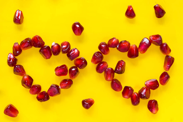 pomegranate seeds are laid out in two hearts on yellow - Valokuva, kuva