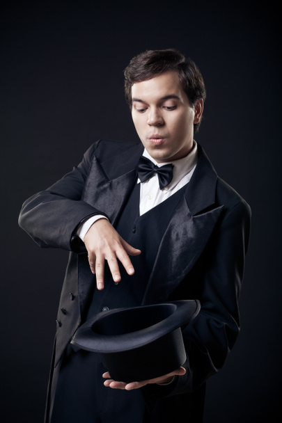 Magician showing tricks with top hat isolated on dark background - Photo, Image