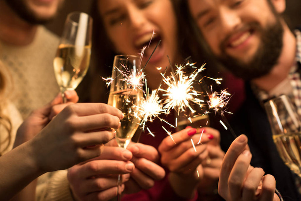 Mensen met glazen champagne en wonderkaarsen  - Foto, afbeelding