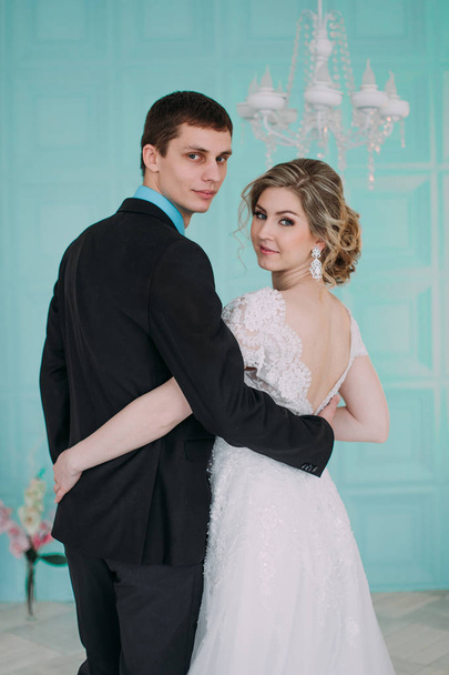Gelukkige paar. Wedding fotoshoot in de witte studio met bruiloft decor kussen, hugs - Foto, afbeelding