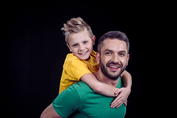 Smiling father piggybacking happy son - 写真・画像