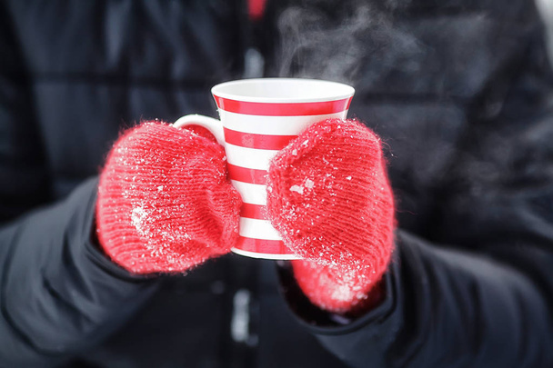 Hands in red mittens holding hot winter mug with steam - Foto, Imagem