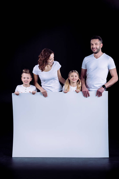 Family standing with blank white card  - Foto, Imagen