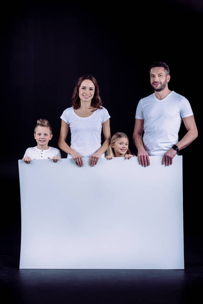 Family standing with blank white card - Φωτογραφία, εικόνα