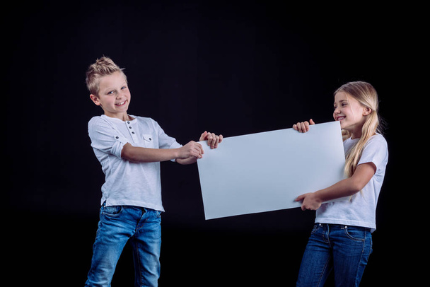 Smiling siblings with blank card - Фото, зображення