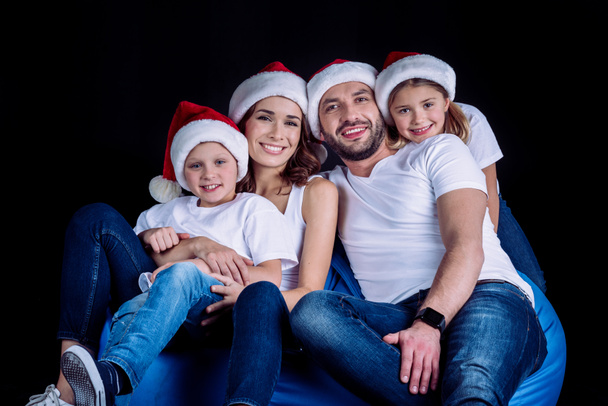 rodina v Santa klobouky při pohledu na fotoaparát - Fotografie, Obrázek
