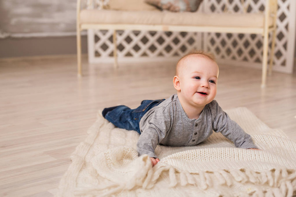Schattige lachende babyjongen in witte zonnige slaapkamer. Pasgeboren kind ontspannen. Familie ochtend thuis. - Foto, afbeelding