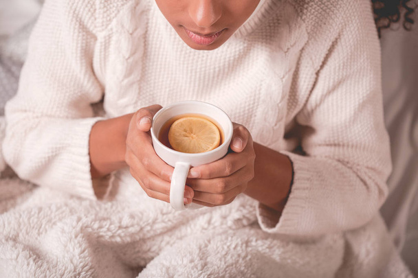 Beyaz bir kazak giyen ve bir fincan çay tutan kadın - Fotoğraf, Görsel