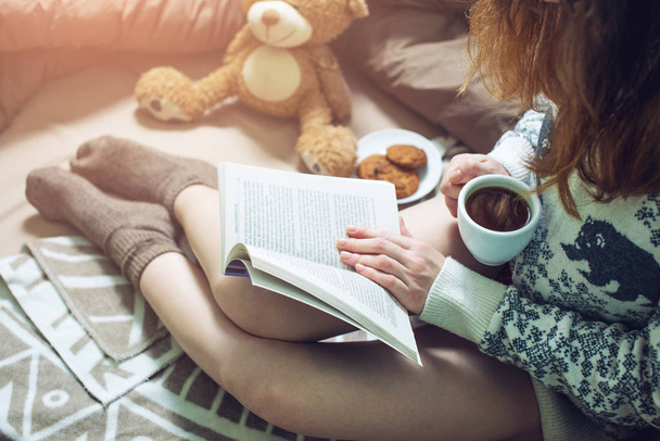 chica leyendo libro en la cama con calcetines calientes beber café
 - Foto, imagen