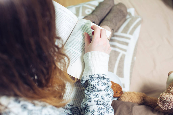 dívka čtení knih v posteli s teplé ponožky pití kávy - Fotografie, Obrázek