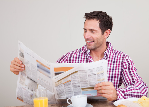 Young Man Reading Newspaper At Breakfast - Фото, зображення