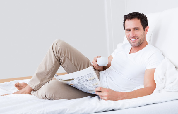 Young Man Holding Cup In Hand Reading Newspaper - Foto, Imagem