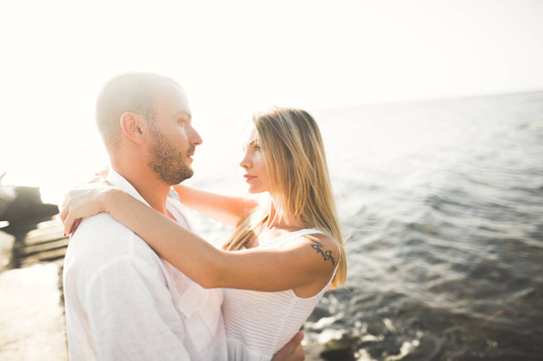 Boda pareja besándose y abrazándose en rocas cerca de mar azul - Foto, imagen