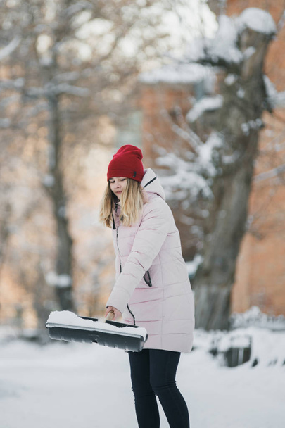 Joven adolescente limpia la nieve cerca de la casa, sosteniendo una pala y remo pasar tiempo
 - Foto, imagen